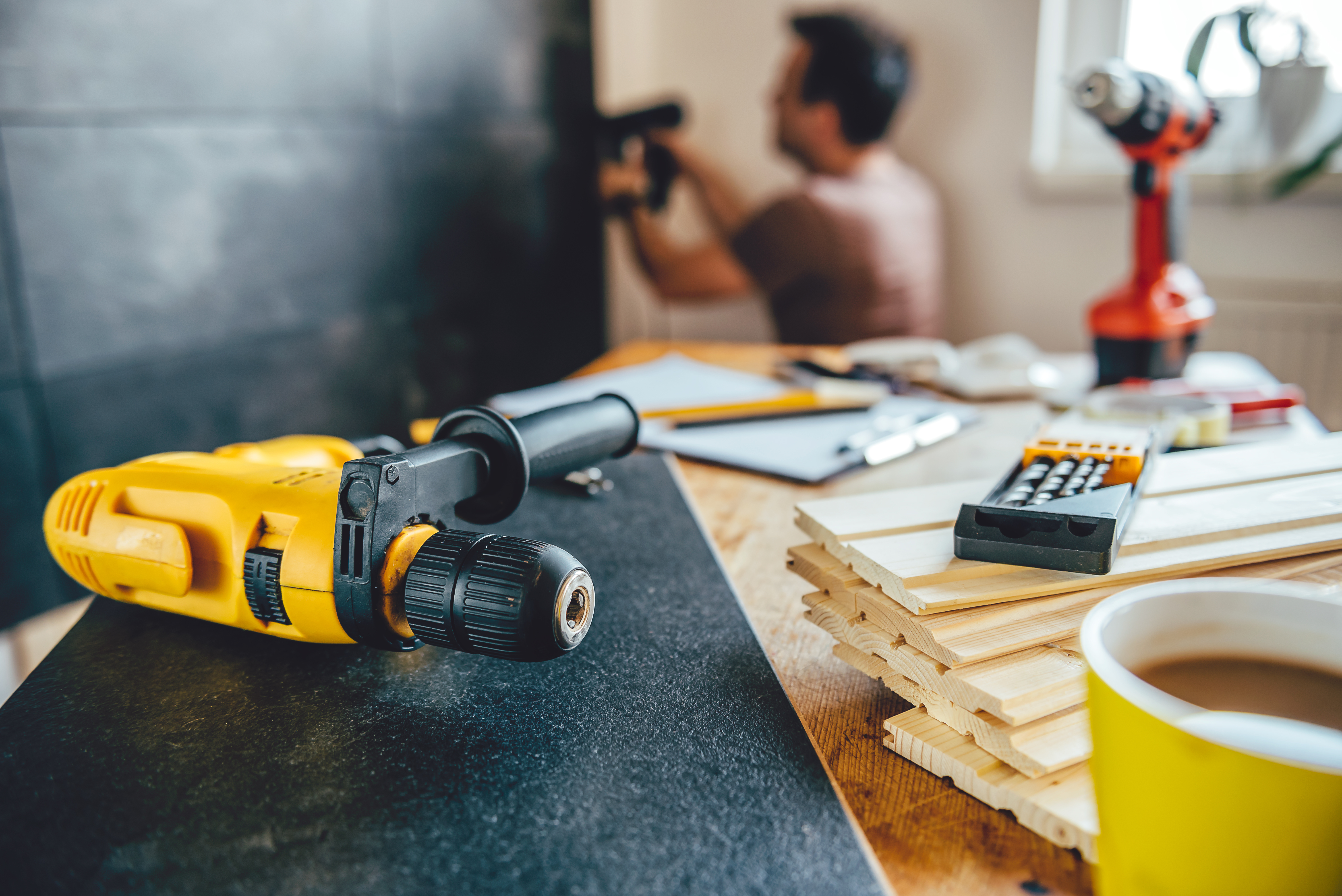 Tools on the table and man renovating wall in the background
