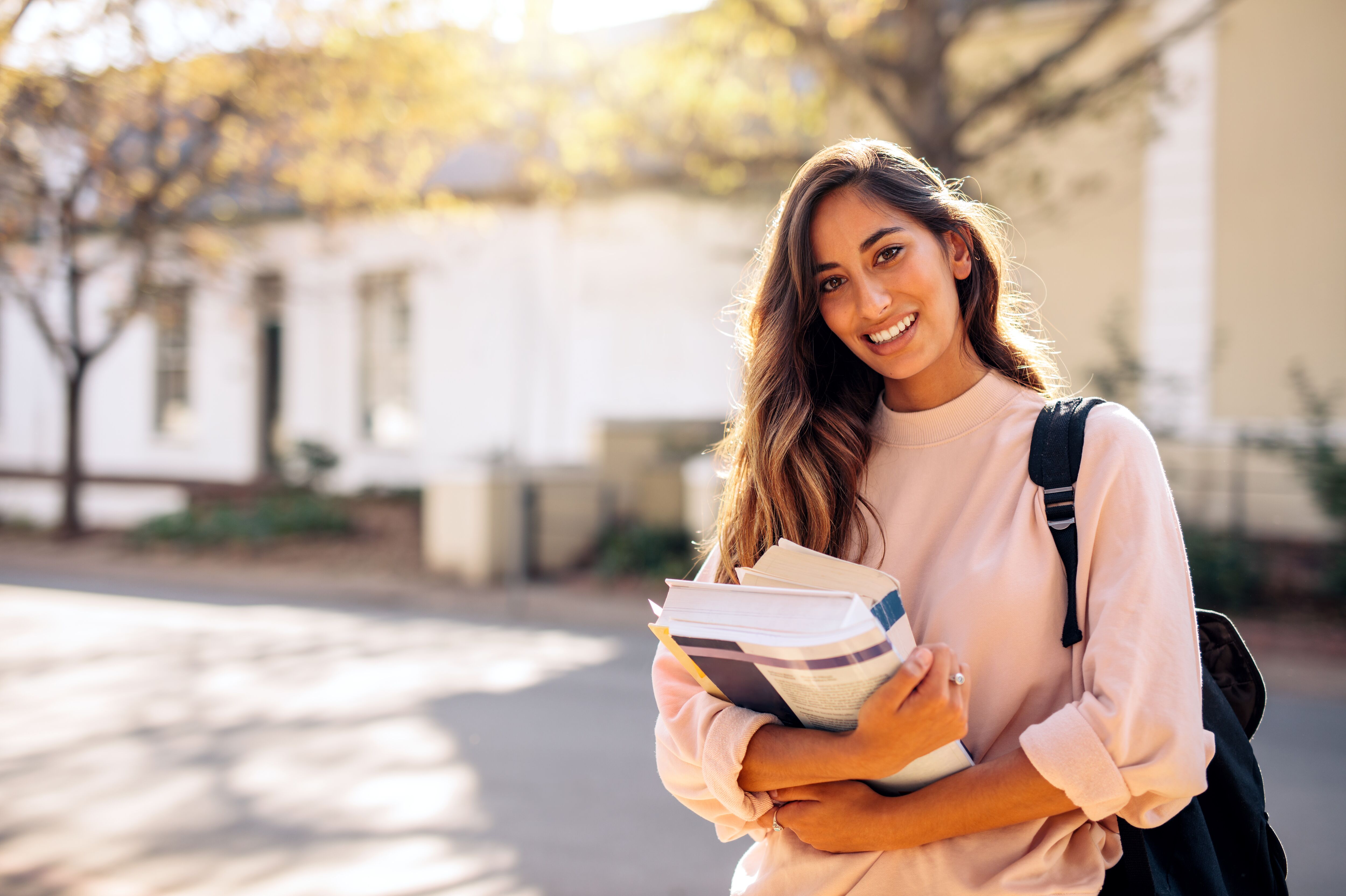 College student carrying lots of books in college campus.