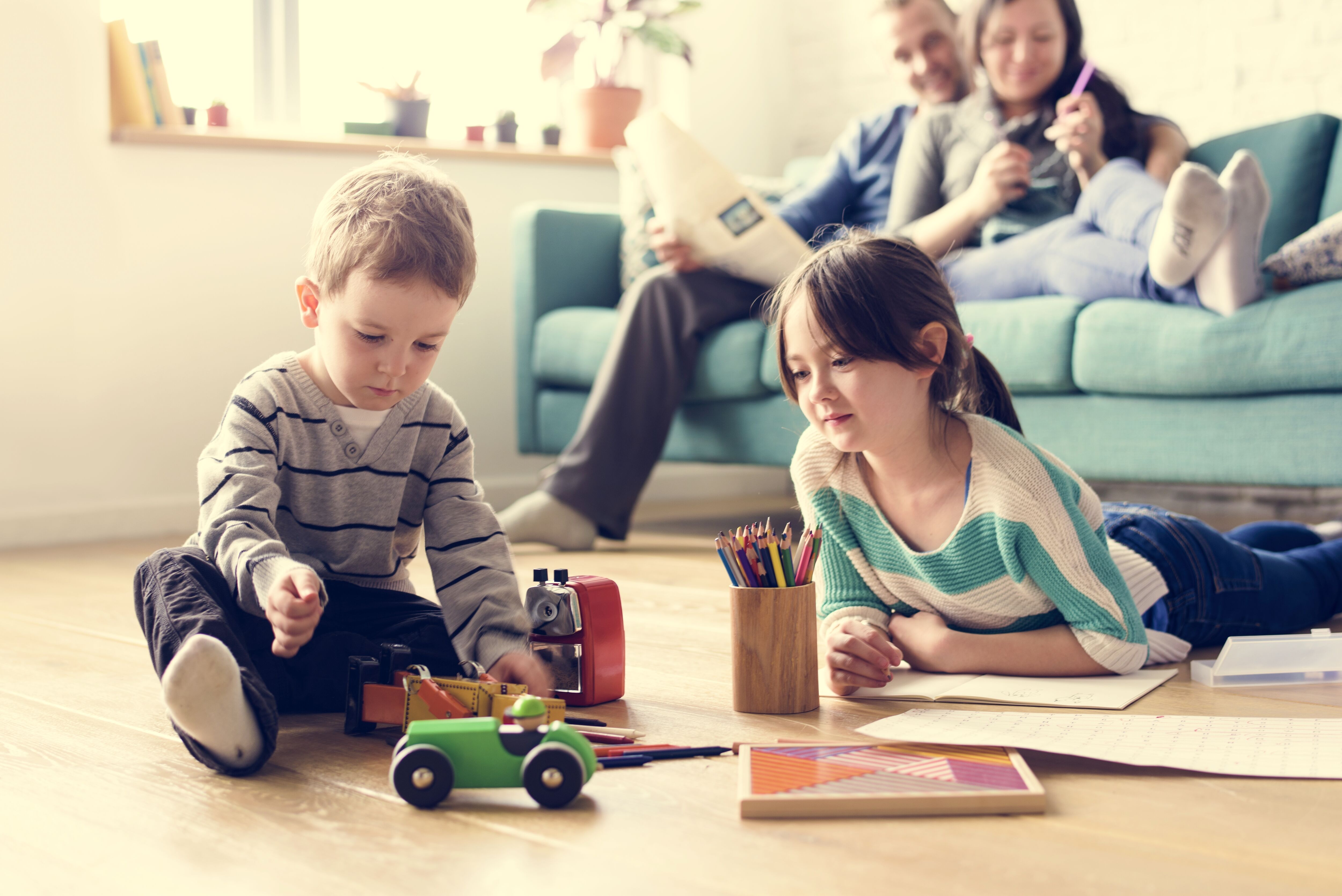 Parents sitting on couch watching kids play on the floor.