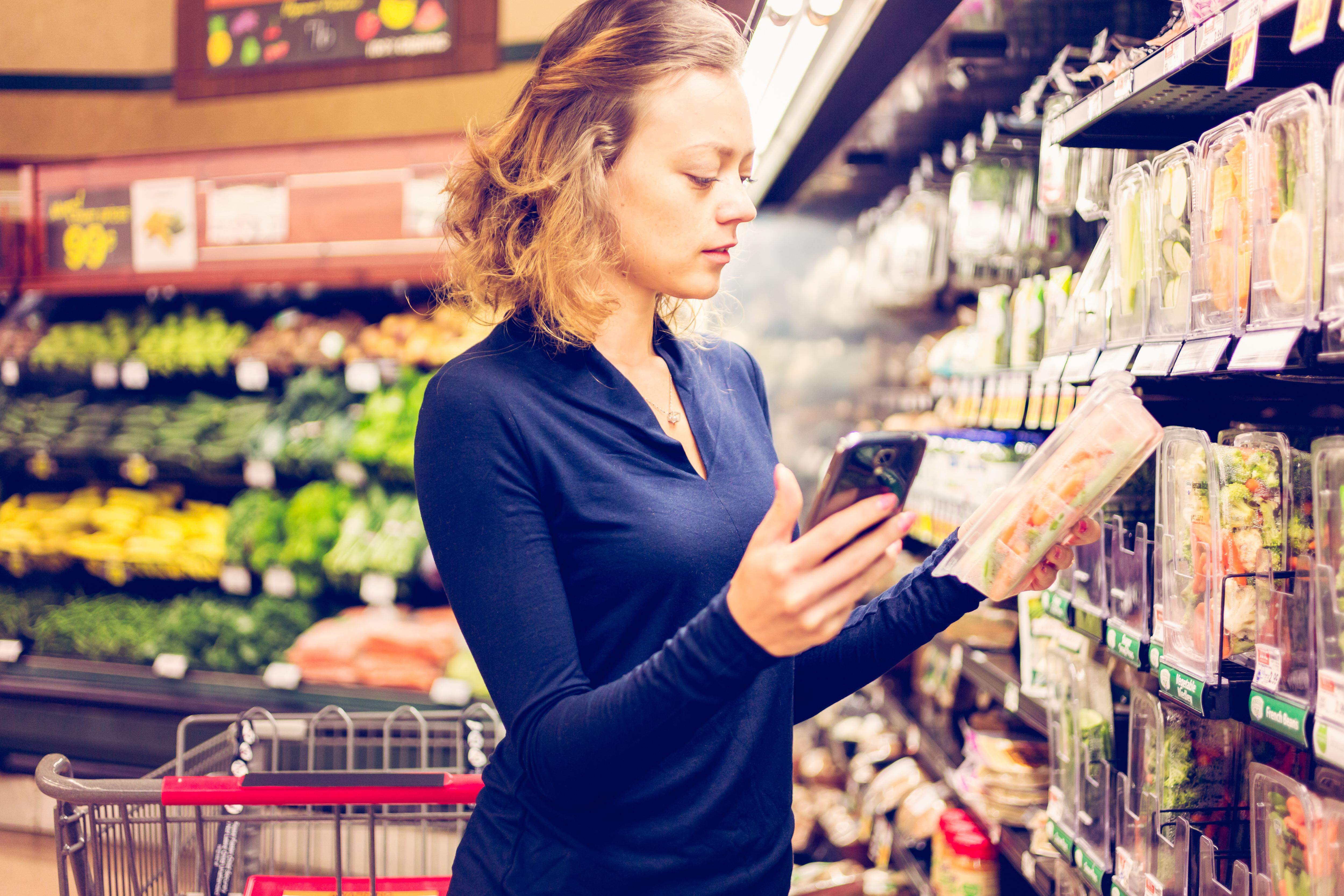 Young woman shopping in the fresh produce section at the grocery store.