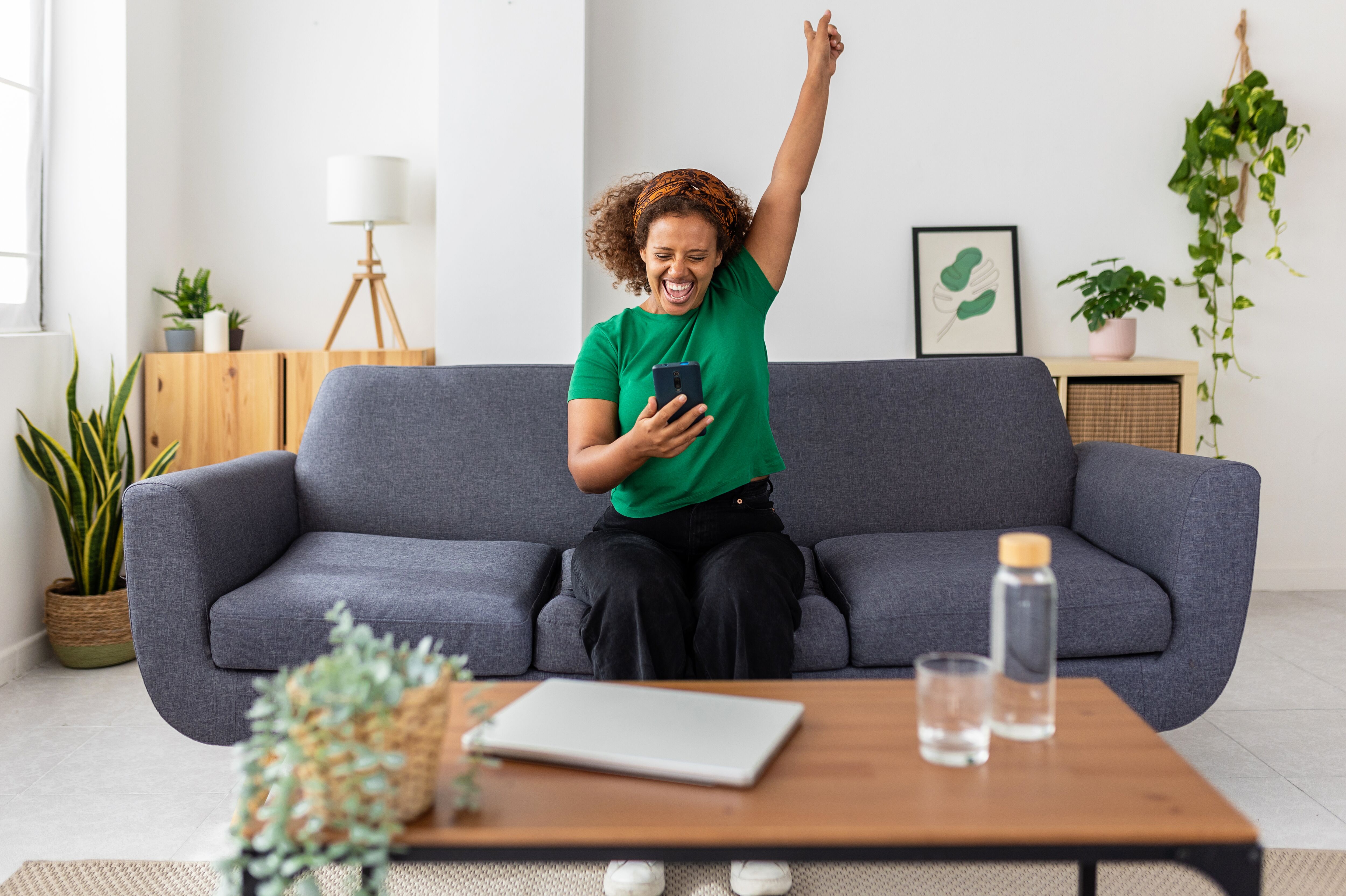 Excited young woman celebrating success looking phone screen.