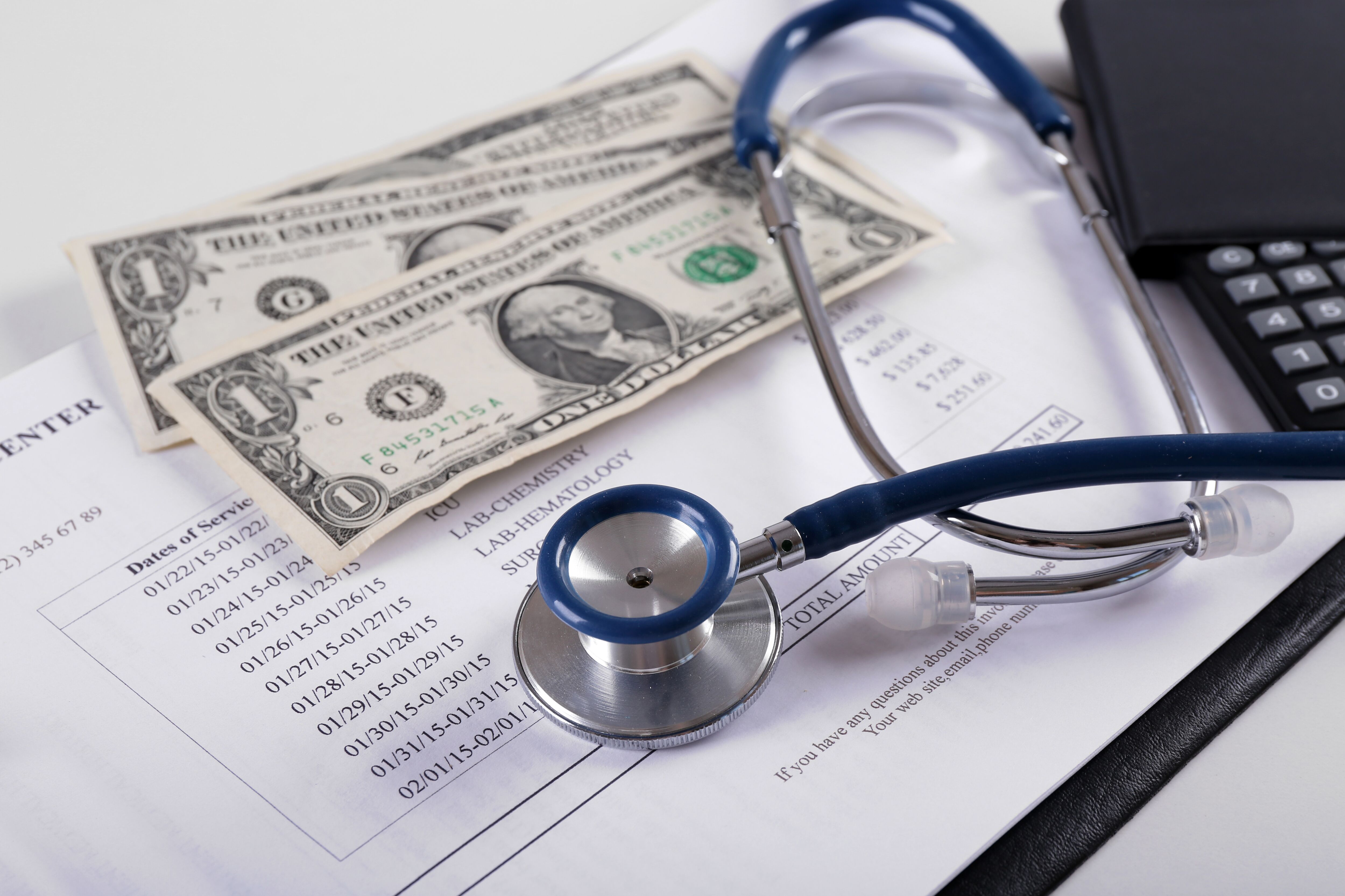 Closeup of a stethoscope, money and medical bill.