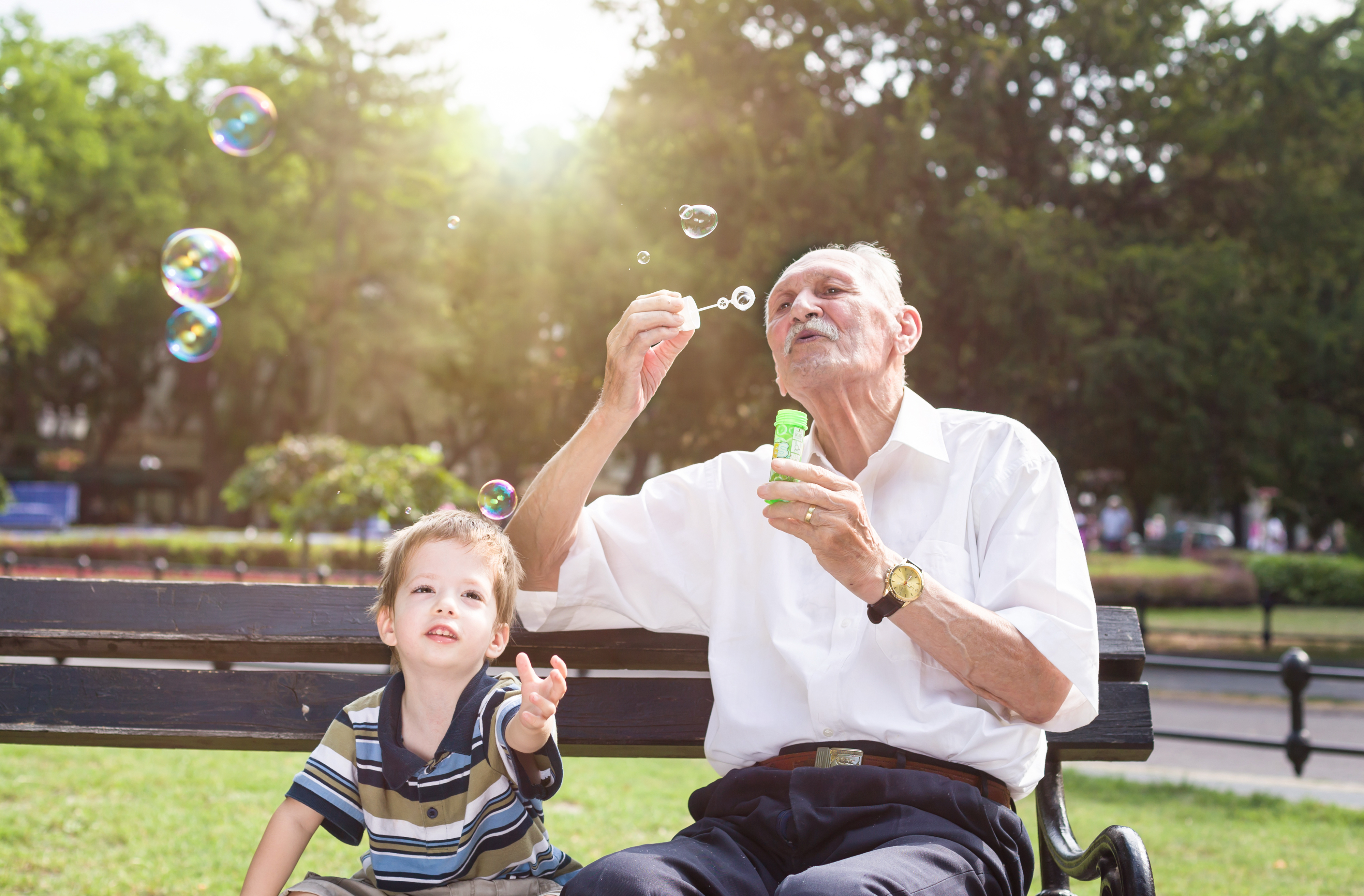 Grandfather blowing soap bubbles to his grand child.